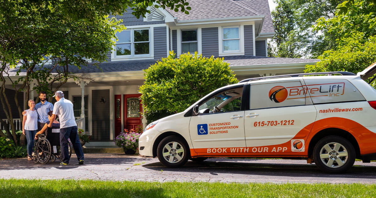 A BriteLift driver helping a rider in a wheelchair beside a BriteLift wheelchair accessible minivan
